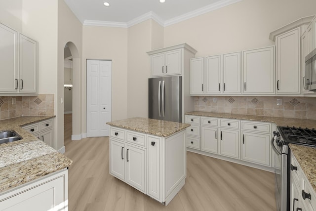 kitchen featuring light stone countertops, a center island, stainless steel appliances, light hardwood / wood-style flooring, and backsplash