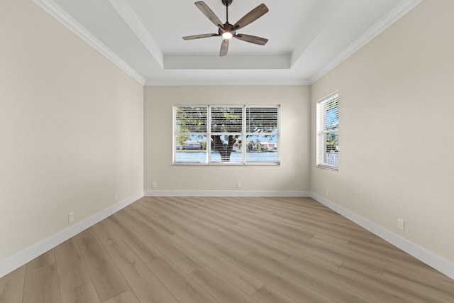 spare room with a tray ceiling, light hardwood / wood-style flooring, plenty of natural light, and crown molding