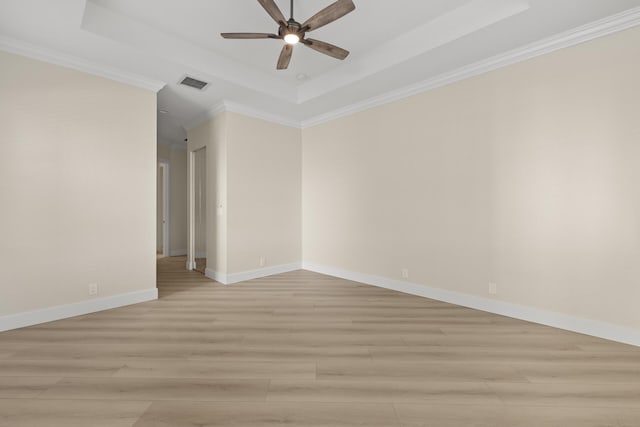 empty room featuring a tray ceiling, light hardwood / wood-style flooring, and ornamental molding