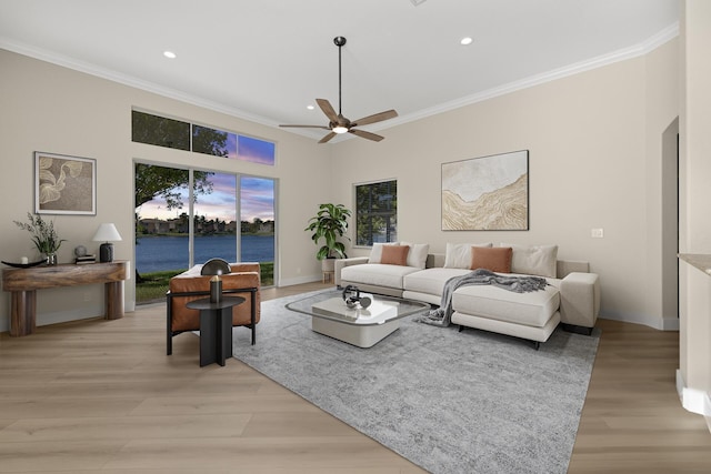 living room featuring light wood-type flooring, a water view, plenty of natural light, and ornamental molding