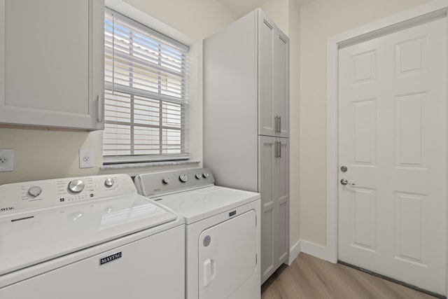 laundry room with washing machine and dryer, light hardwood / wood-style flooring, and cabinets