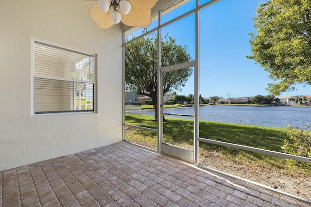 unfurnished sunroom with a water view and ceiling fan