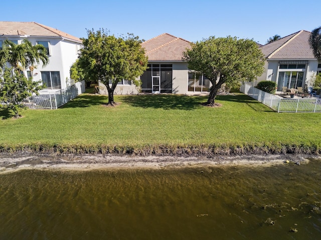 rear view of property featuring a water view and a yard