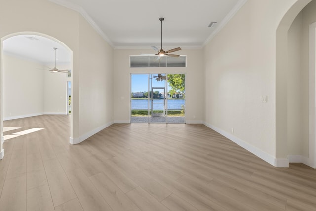 unfurnished room with ceiling fan with notable chandelier, a water view, light wood-type flooring, and crown molding