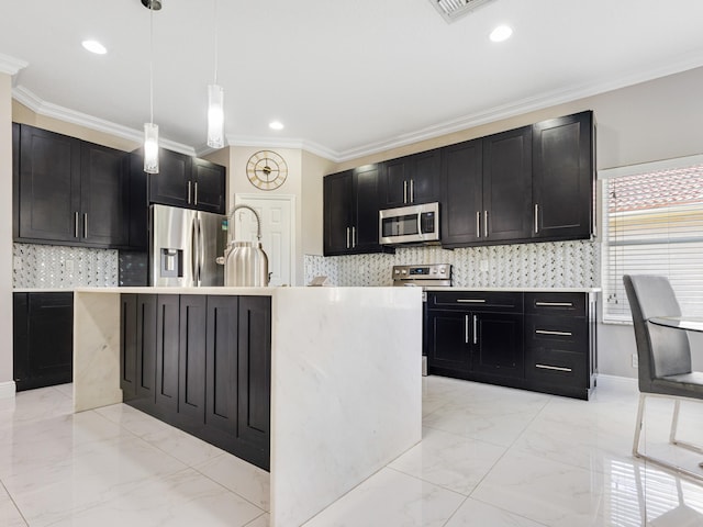 kitchen with pendant lighting, appliances with stainless steel finishes, crown molding, and a center island with sink