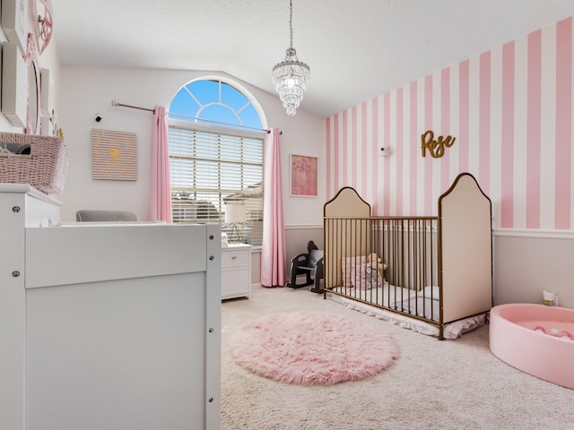 carpeted bedroom with vaulted ceiling, a textured ceiling, and a crib