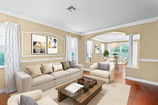 living room featuring hardwood / wood-style floors, ornate columns, ornamental molding, and a textured ceiling