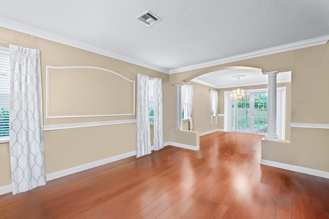 unfurnished room featuring hardwood / wood-style floors, crown molding, a textured ceiling, and decorative columns