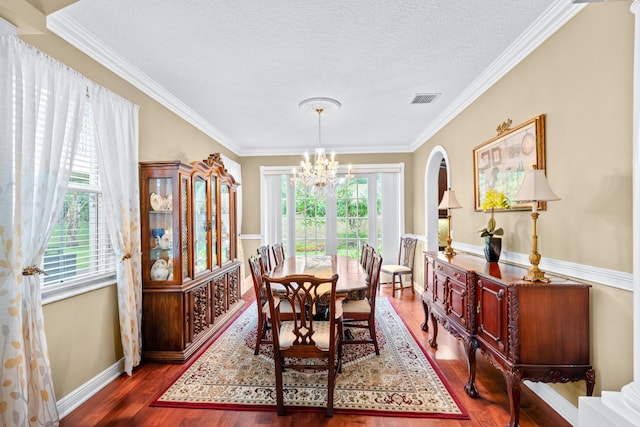 dining room featuring a healthy amount of sunlight, dark hardwood / wood-style flooring, ornamental molding, and a textured ceiling