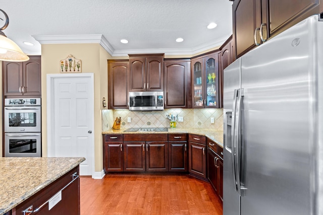 kitchen featuring light stone countertops, dark hardwood / wood-style floors, backsplash, appliances with stainless steel finishes, and ornamental molding