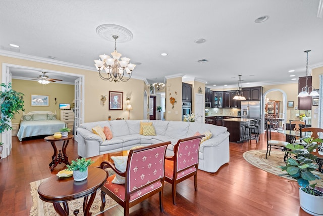 living room with crown molding, dark hardwood / wood-style flooring, and ceiling fan with notable chandelier