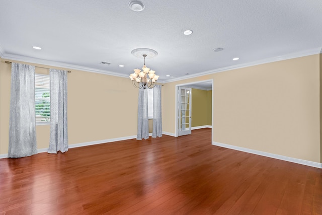 spare room with a textured ceiling, a notable chandelier, dark hardwood / wood-style flooring, and crown molding