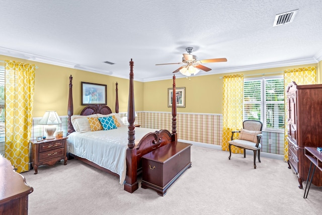 bedroom with a textured ceiling, light colored carpet, ceiling fan, and ornamental molding