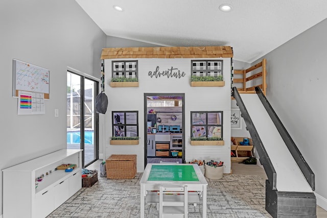 playroom with lofted ceiling and a textured ceiling