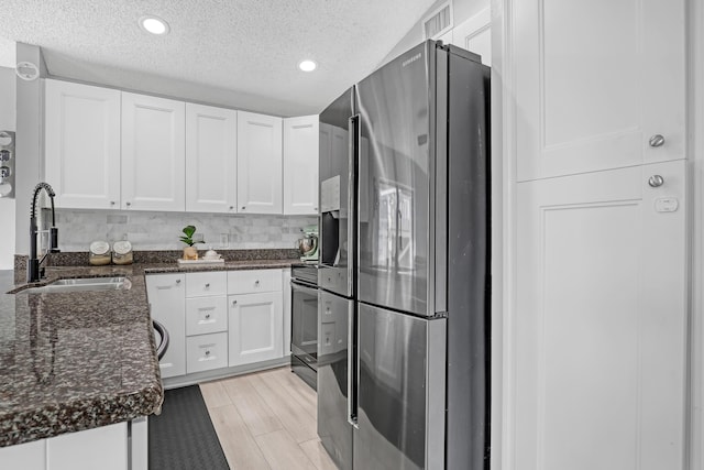 kitchen featuring white cabinets, stainless steel fridge, and sink