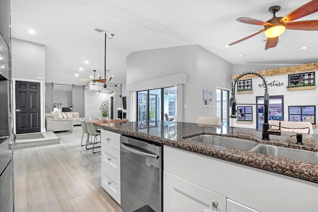 kitchen featuring white cabinetry, sink, dishwasher, dark stone counters, and lofted ceiling