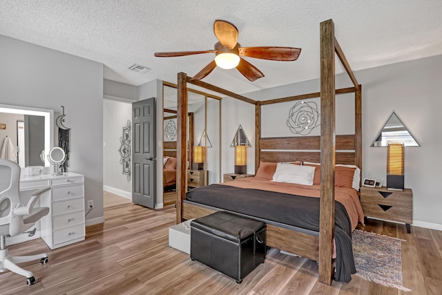 bedroom featuring ceiling fan, light wood-type flooring, and a textured ceiling