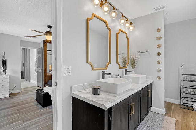 bathroom featuring hardwood / wood-style floors, ceiling fan, a textured ceiling, and vanity