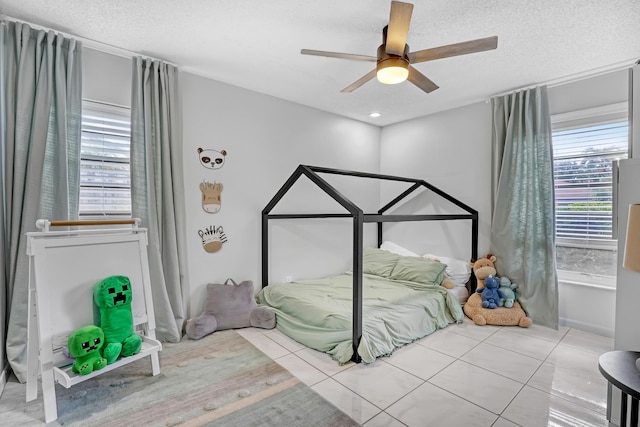 bedroom featuring light tile patterned floors, a textured ceiling, and ceiling fan