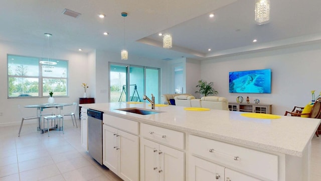 kitchen with stainless steel dishwasher, decorative light fixtures, a center island with sink, and a wealth of natural light