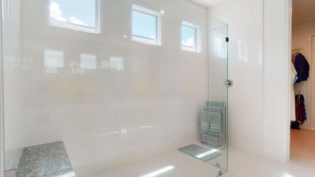 bathroom featuring tile patterned flooring, a tile shower, and a wealth of natural light