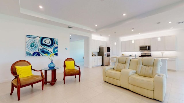 living room with a tray ceiling and sink