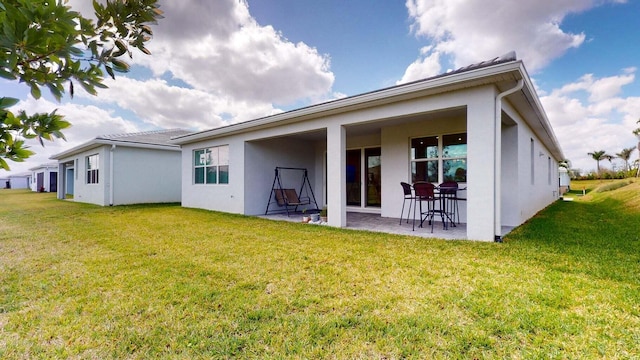 rear view of house featuring a lawn and a patio