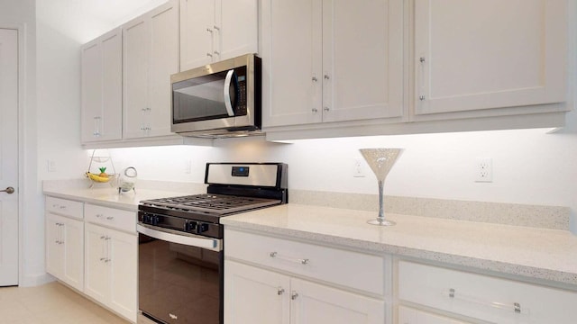 kitchen featuring light stone countertops, stainless steel appliances, and white cabinetry