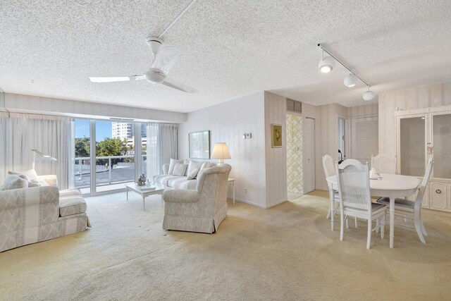 living room featuring ceiling fan, rail lighting, light colored carpet, and a textured ceiling