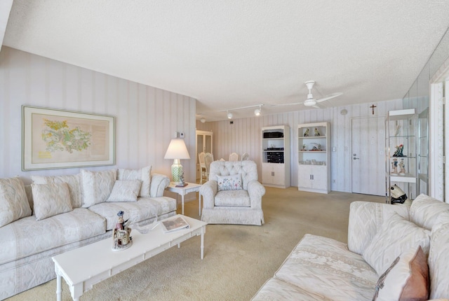 living room with light carpet, ceiling fan, and a textured ceiling