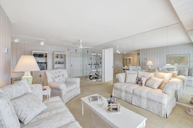 living room with a textured ceiling, light colored carpet, and ceiling fan