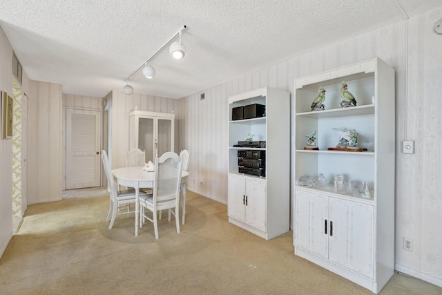 carpeted dining room with a textured ceiling