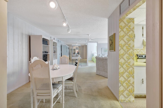 dining space with a textured ceiling, light colored carpet, and ceiling fan