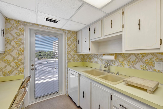 kitchen with sink, white dishwasher, a paneled ceiling, light carpet, and white cabinets