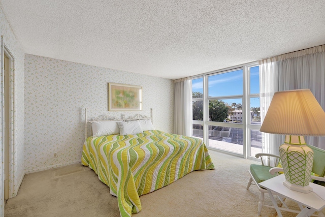 carpeted bedroom featuring a textured ceiling, access to outside, and a wall of windows