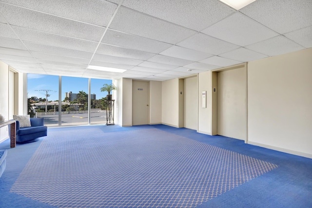 basement with a paneled ceiling, carpet floors, and elevator