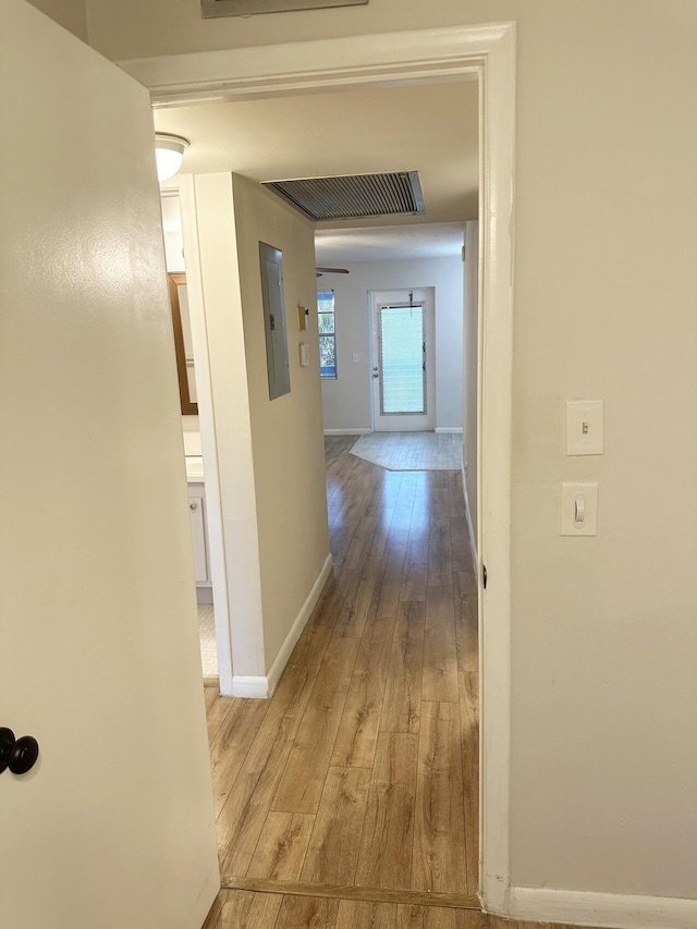 hallway with light hardwood / wood-style floors and electric panel