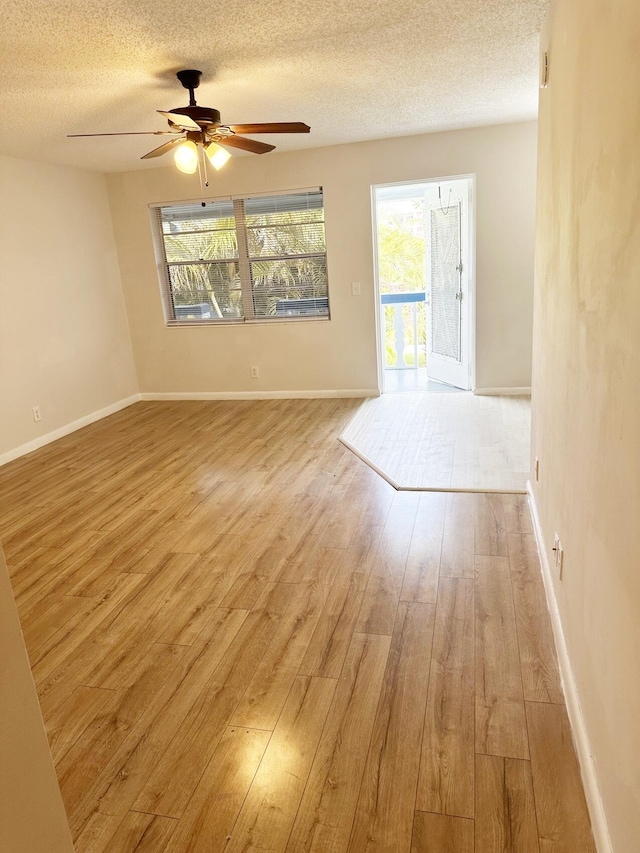 unfurnished room with a textured ceiling, light wood-type flooring, and ceiling fan