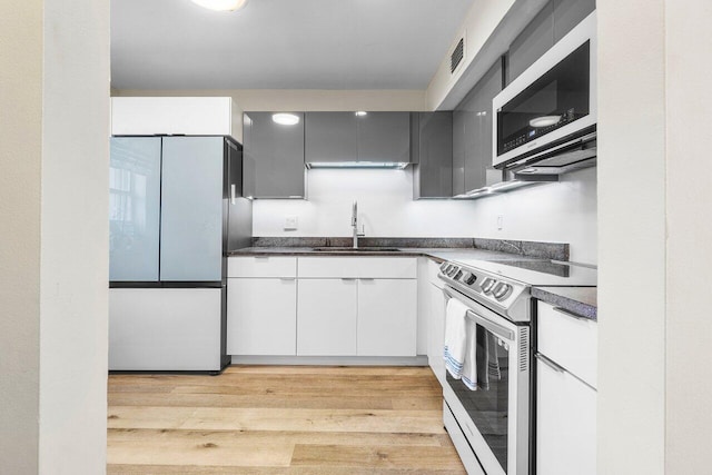 kitchen with white cabinetry, sink, range with electric stovetop, white fridge, and light wood-type flooring