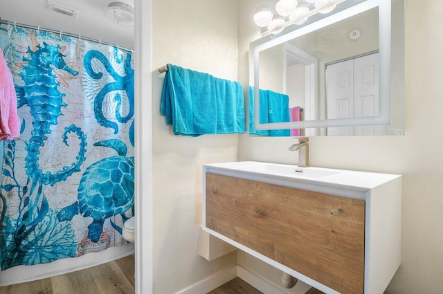 bathroom with a shower with curtain, vanity, wood-type flooring, and toilet