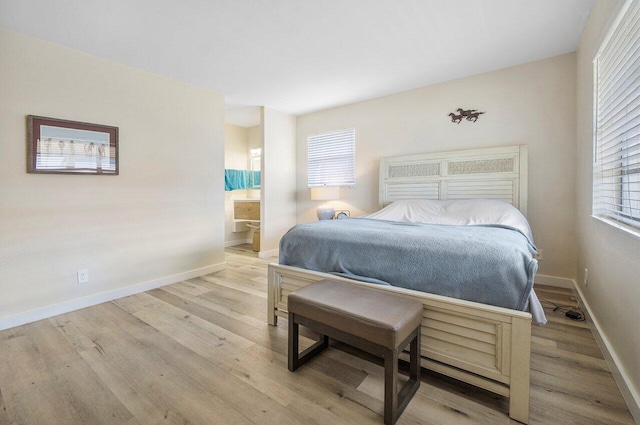 bedroom featuring ensuite bathroom, light hardwood / wood-style floors, and multiple windows