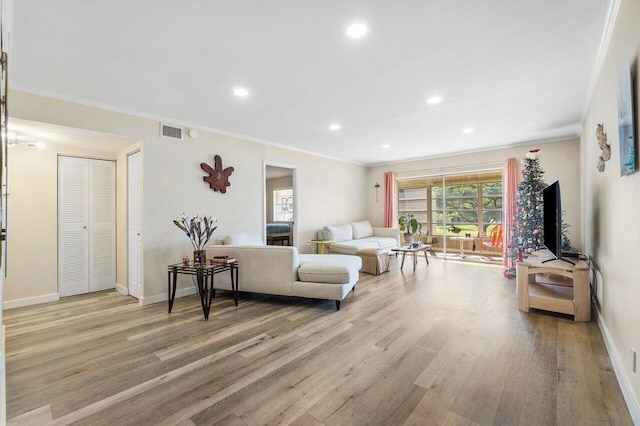 living room with light hardwood / wood-style flooring and crown molding