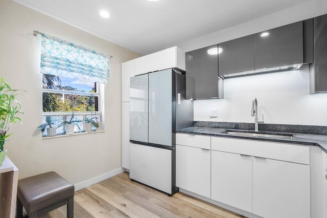 kitchen with light hardwood / wood-style flooring, white cabinetry, fridge, and sink