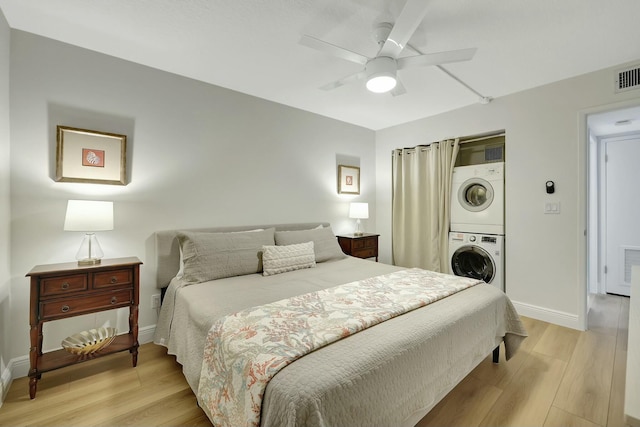 bedroom with ceiling fan, light hardwood / wood-style floors, and stacked washer and clothes dryer