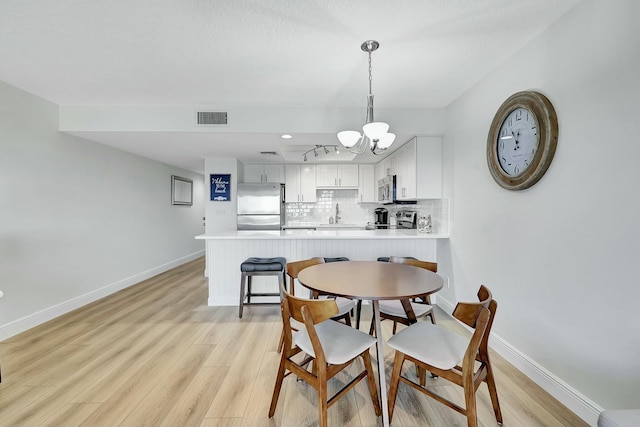 dining room with light hardwood / wood-style floors and a notable chandelier