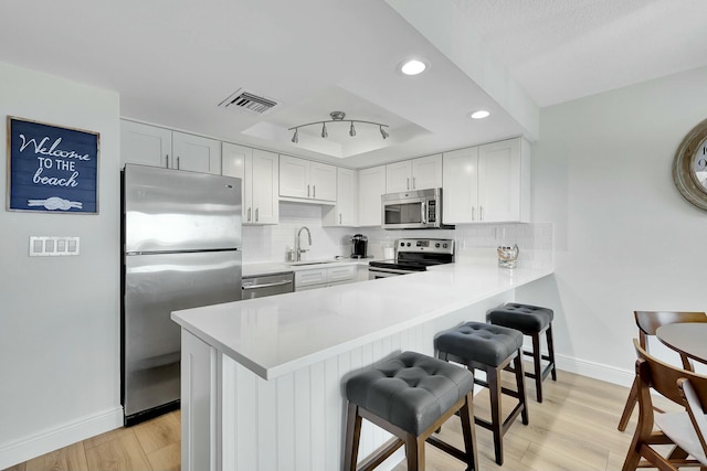 kitchen with white cabinets, appliances with stainless steel finishes, light hardwood / wood-style flooring, and sink