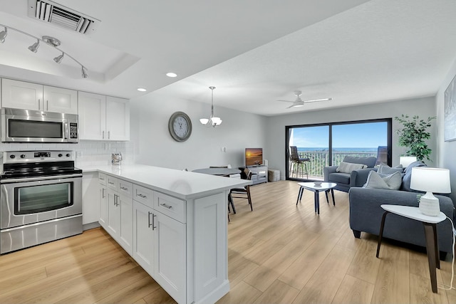 kitchen with white cabinets, appliances with stainless steel finishes, kitchen peninsula, and light hardwood / wood-style floors