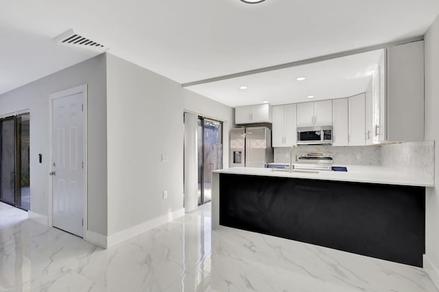 kitchen with kitchen peninsula, sink, white cabinets, and stainless steel appliances