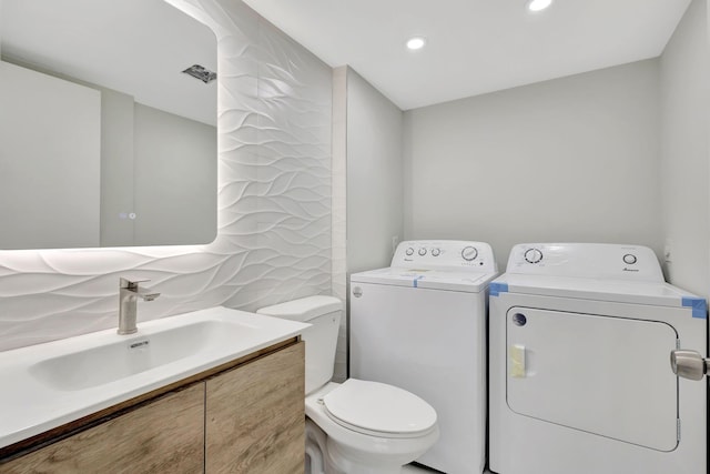 bathroom featuring separate washer and dryer, decorative backsplash, vanity, and toilet