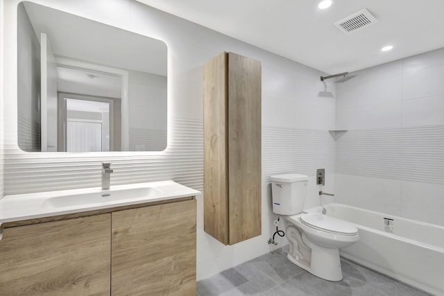 full bathroom featuring tile patterned floors, toilet, vanity, tile walls, and tiled shower / bath